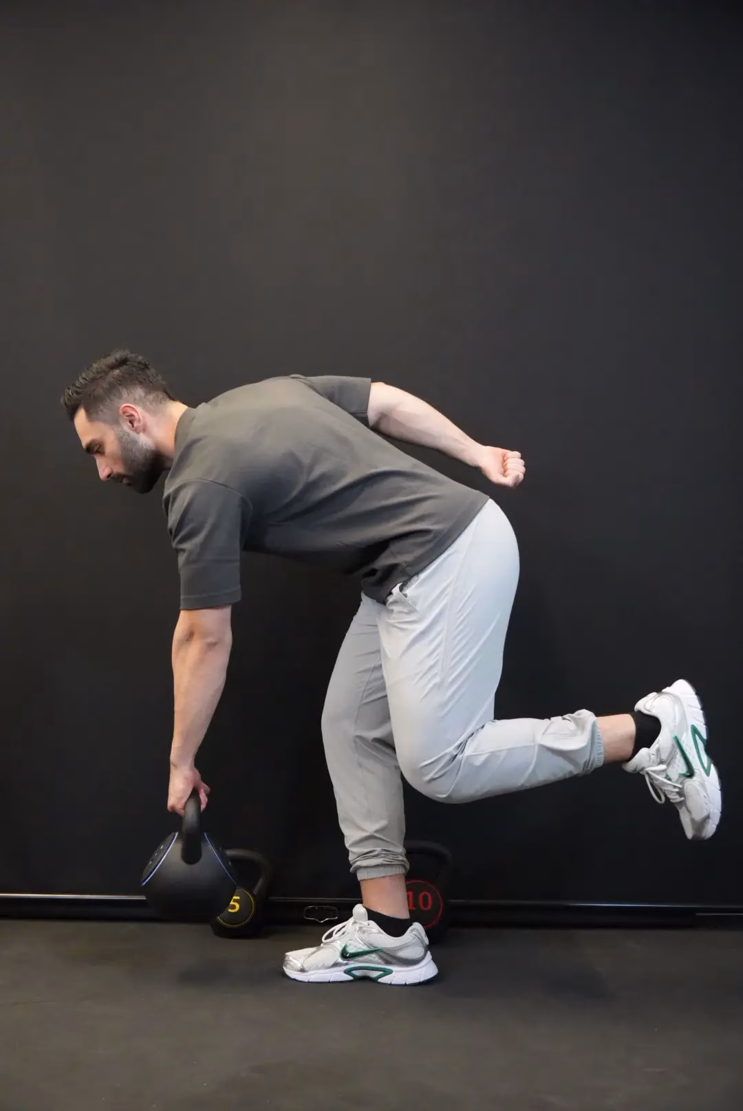 A man performs a single-leg Romanian deadlift with a kettlebell in one hand, demonstrating strength and balance—an exercise often recommended by Mobile Physiotherapy Vancouver to enhance stability and functional fitness.